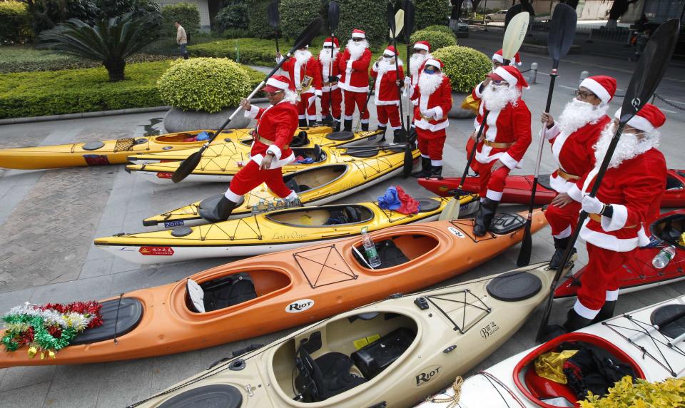 Members of a local kayak club dressed as Santa Claus prepare to take their kayaks into Zhujiang River during a promotional event to celebrate Christmas in Guangzhou, Guangdong province, December 25, 2013. REUTERS/Stringer (CHINA - Tags: SOCIETY) CHINA OUT. NO COMMERCIAL OR EDITORIAL SALES IN CHINA