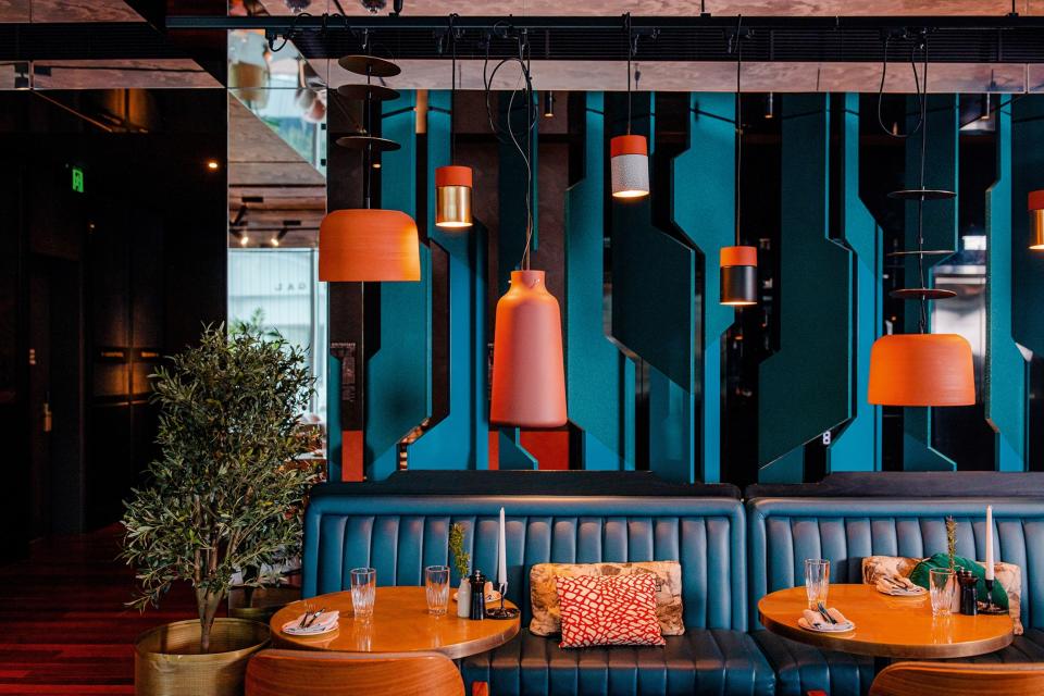 Restaurant with blue leather sofas, sofa cushions and hanging lights with orange lampshades