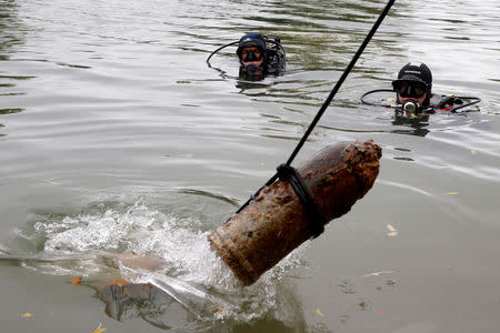 Divers from a bomb-disposal unit look at an unexploded shell recovered in the Meuse River at Sivry-sur-Meuse, close to WW1 battlefields, France, October 24, 2018 before the centennial commemoration of the First World War Armistice Day. REUTERS/Pascal Rossignol