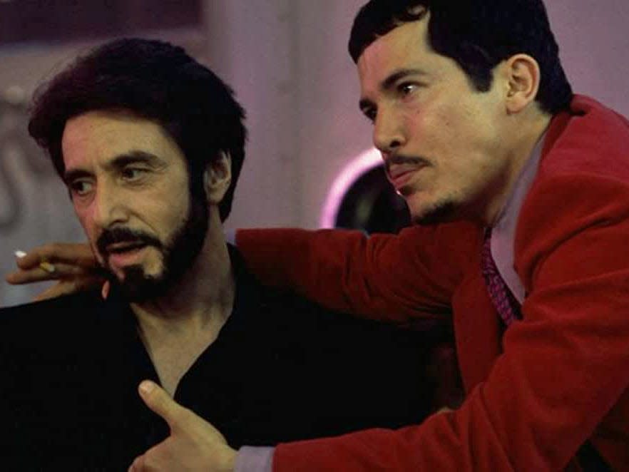 John Leguizamo in a red jacket with his arm around Al Pacino in a black jacket