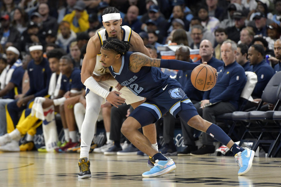 Memphis Grizzlies guard Ja Morant (12) handles the ball against Indiana Pacers guard Andrew Nembhard, top, in the first half of an NBA basketball game Thursday, Dec. 21, 2023, in Memphis, Tenn. (AP Photo/Brandon Dill)