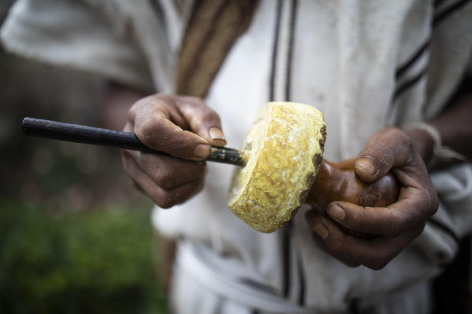 An Arhuaco Indigenous man holds a poporo as he chews coca leaves in Nabusimake on the Sierra Nevada de Santa Marta, Colombia, Sunday, Jan. 15, 2023. A poporo carries small amounts of lime produced from burnt and crushed sea-shells, it includes a wooden pin that is used to carry the lime inside the poporo to the mouth while chewing coca leaves. The lime will release the alkaloids in coca leaf. (AP Photo/Ivan Valencia)