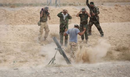 Shiite fighters launch a mortar round toward Islamic State militants in Baiji, north of Baghdad, October 14, 2015. REUTERS/Stringer