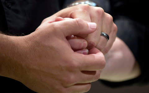 A couple hold hands during their wedding ceremony - Credit:  AP