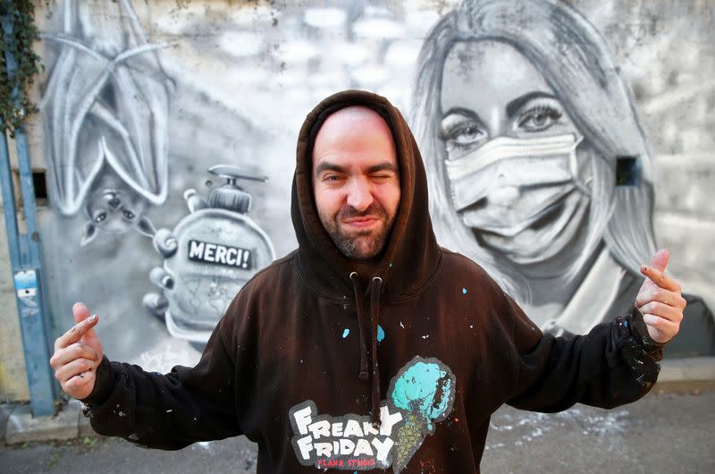 Artist Perez takes poses in front of his graffiti of a cashier to pay tribute to essential workers in Gland