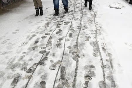 Pedestrians walk through freshly fallen snow on a sidewalk during a snow storm in New York March 3, 2015. REUTERS/Lucas Jackson