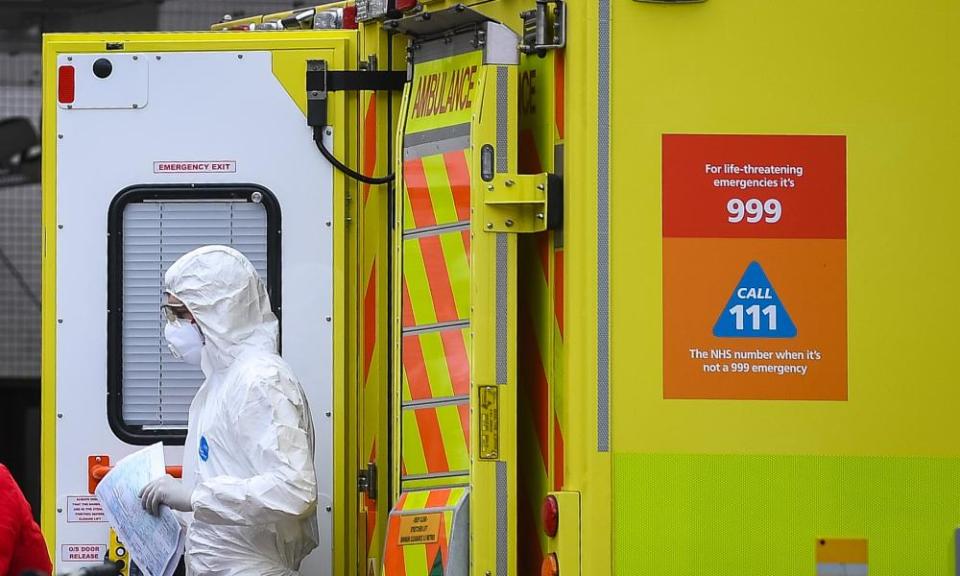 A paramedic wearing personal protective equipment (PPE) exits an ambulance.