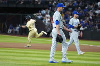Chicago Cubs pitcher Drew Smyly, center, and Cubs first baseman Michael Busch, right, walk off the field as Arizona Diamondbacks' Randal Grichuk (15) celebrates his double that drove in the winning run during the 10th inning of a baseball game Tuesday, April 16, 2024, in Phoenix. The Diamondbacks won 12-11. (AP Photo/Ross D. Franklin)