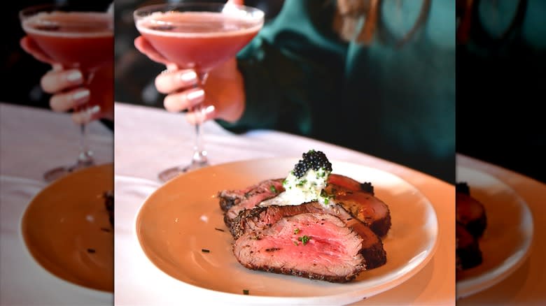 Person with steak and cocktail