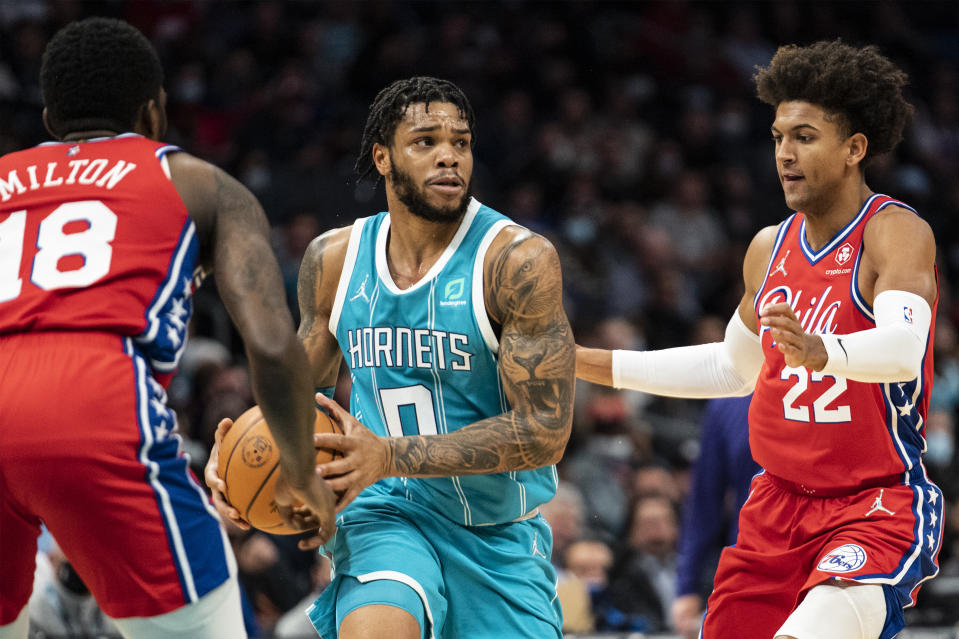 Charlotte Hornets forward Miles Bridges (0) looks to pass while being guarded by Philadelphia 76ers guard Matisse Thybulle (22) and guard Shake Milton (18) during the first half of an NBA basketball game, Wednesday, Dec. 8, 2021, in Charlotte, N.C. (AP Photo/Matt Kelley)