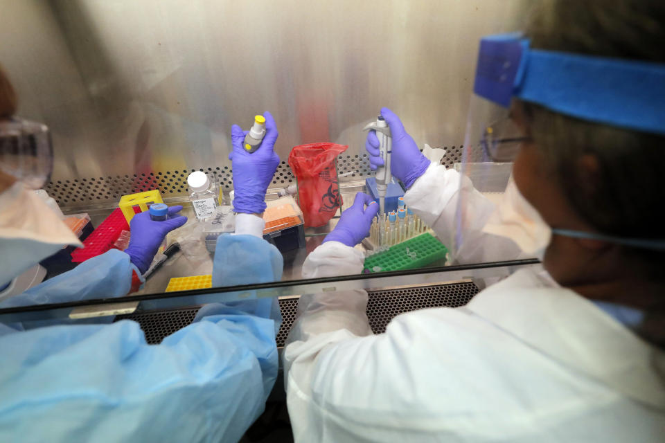 FILE - In this April 2, 2020 file photo, Cindy Morris, left, and Swarnamala Ratnayaka prepare RNA for testing for the new coronavirus at the molecular pathology lab at Tulane University School of Medicine in New Orleans. Where political divides marred early recovery efforts after Hurricane Katrina in 2005, Louisiana is showing rare political unity in the fight against the new coronavirus. (AP Photo/Gerald Herbert, File)