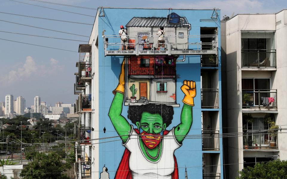Brazilian artist Mundano works on a graffiti called "Heroinas Invisiveis" (invisible heroines), a tribute to the women during the outbreak of the coronavirus at Heliopolis slum in Sao Paulo - Reuters