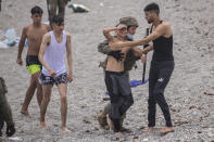 A boy is assisted by a soldier of the Spanish Army near the border of Morocco and Spain, at the Spanish enclave of Ceuta, on Tuesday, May 18, 2021. Ceuta, a Spanish city of 85,000 in northern Africa, faces a humanitarian crisis after thousands of Moroccans took advantage of relaxed border control in their country to swim or paddle in inflatable boats into European soil. (AP Photo/Bernat Armangue)