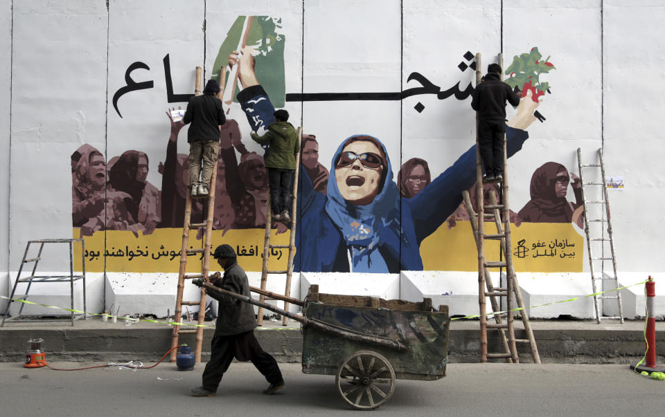 FIILE - In this March 8, 2019 file photo, an independent Afghan artists draws graffiti on a barrier wall of the Ministry of Women's Affairs to mark International Women's Day, in Kabul, Afghanistan. In a Thursday, March 28, 2019 report the Special Inspector General for Afghan Reconstruction, a U.S. watchdog, said that Afghanistan will remain dependent on international donors and foreign help even after a peace deal with the Taliban is reached. The report identified main high-risk areas including threats to women's rights. (AP Photo/Rahmat Gul, File)