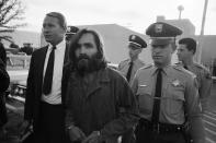 <p>Charles Manson, leader of a hippie cult accused of multiple murders, leaves a Los Angeles courtroom on Dec. 22, 1969, after telling a judge “Lies have been told” about him. His followers said the 35-year-old ex-convict has hypnotic powers. At left is his public defender, Fred Schaefer. (Photo: Wally Fong/AP) </p>