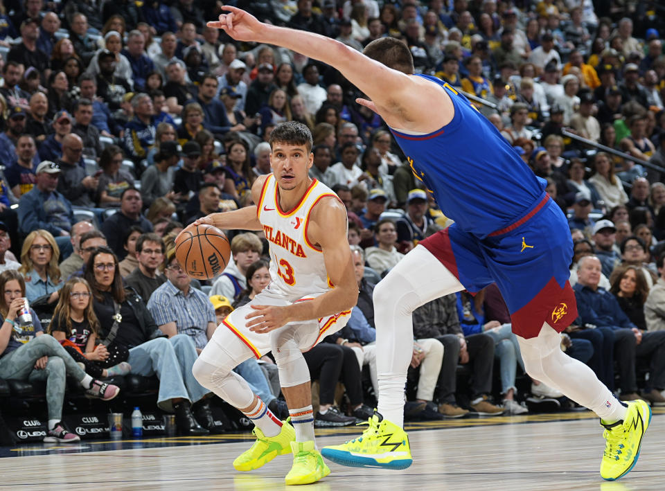 Atlanta Hawks guard Bogdan Bogdanovic, left, looks to drive past Denver Nuggets center Nikola Jokic in the first half of an NBA basketball game Saturday, April 6, 2024, in Denver. (AP Photo/David Zalubowski)