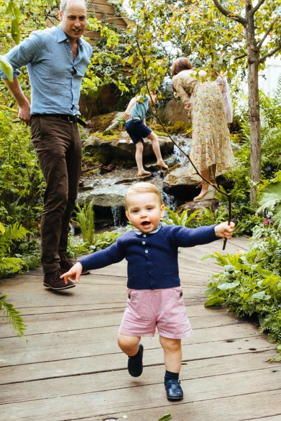 Prince William watches on as Prince Louis walks while holding a branch (EPA)