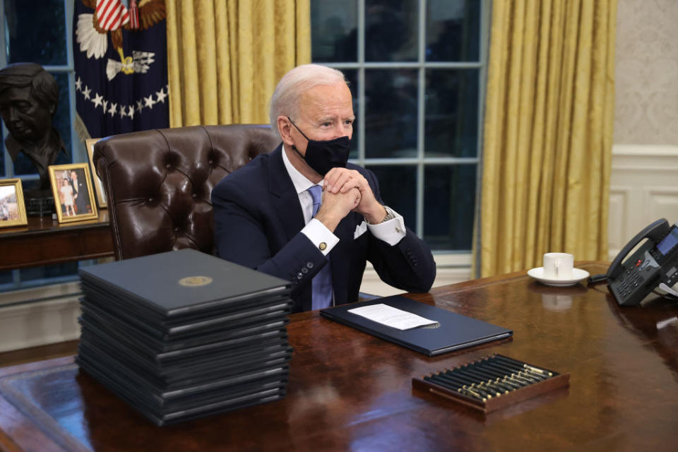 US President Joe Biden prepares to sign a series of executive orders at the Resolute Desk in the Oval Office.