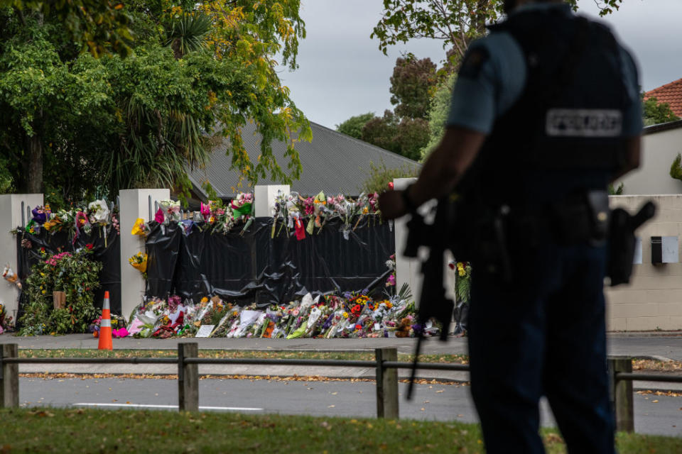 Flowers lie by the wall of Al Noor mosque as an armed policeman guards nearby on March 21, 2019 in the wake of the attacks. Source: Getty