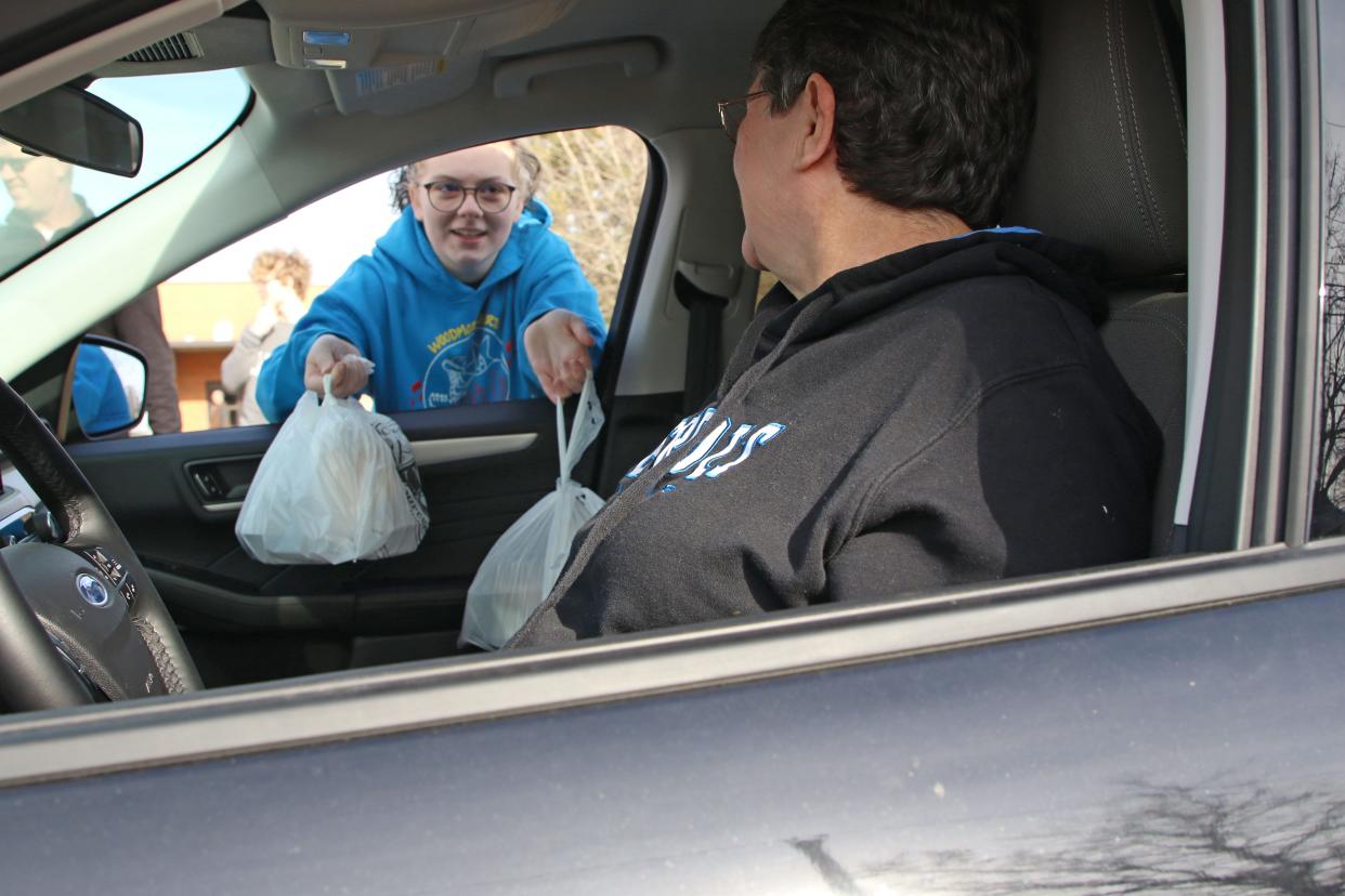 Ava Rich, 17, passes out free Thanksgiving dinners at a drive-thru set up at Woodmore High School, on Thanksgiving morning. Over 50 volunteers passed out 600 meals during the 14th annual event on Thursday