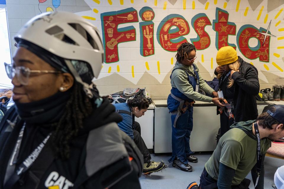 Natasha Blakely, center, of Detroit, helps Savanna Roberts, right, of Atlanta, get her harness set while checking out gear to ice climb with others from their group at Central Elementary School in Munising on Thursday, Feb. 9, 2023, during the Michigan Ice Fest in Michigan's Upper Peninsula.