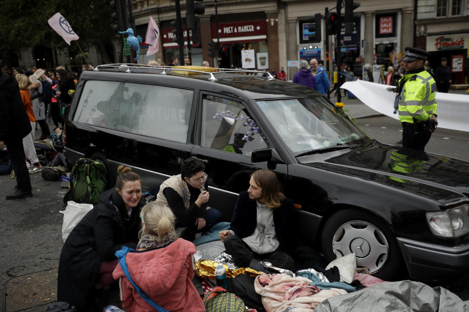 Extinction Rebellion climate change demonstrators block a road with a hearse where Trafalgar Square joins Whitehall in London, Tuesday, Oct. 8, 2019. Hundreds of climate change activists camped out in central London on Tuesday during a second day of world protests by the Extinction Rebellion movement to demand more urgent actions to counter global warming. (AP Photo/Matt Dunham)