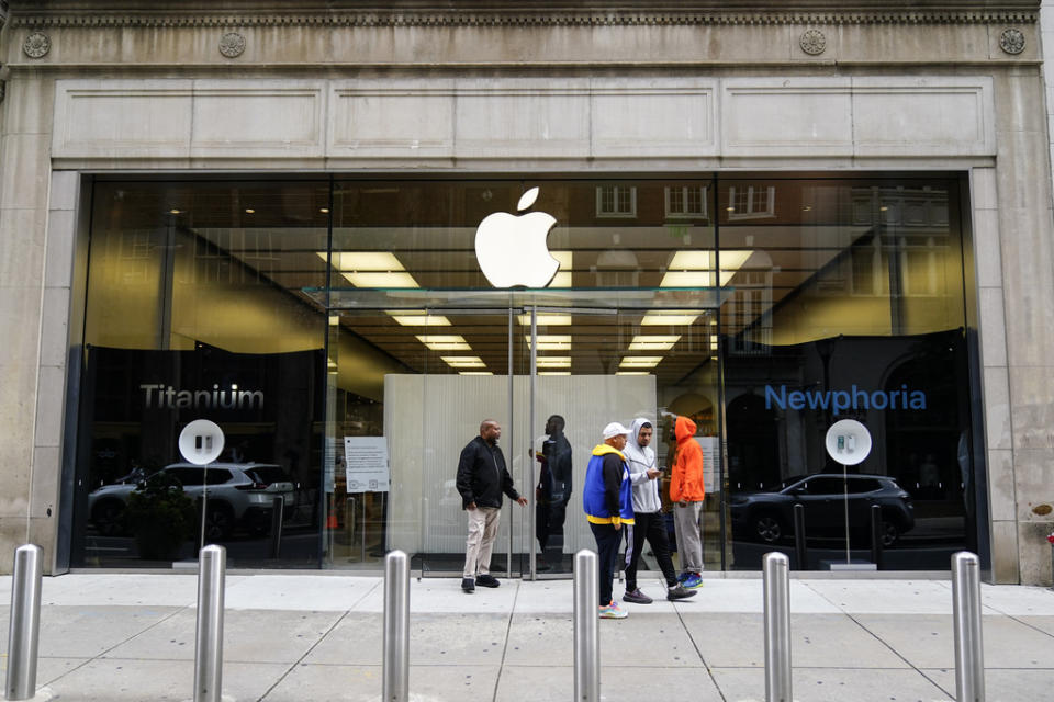 People stand outside an Apple Store in Philadelphia, Wednesday, Sept. 27, 2023 after it was ransacked the previous evening. Police say groups of teenagers swarmed into stores across Philadelphia in an apparently coordinated effort, stuffed bags with merchandise and fled. (AP Photo/Matt Rourke)