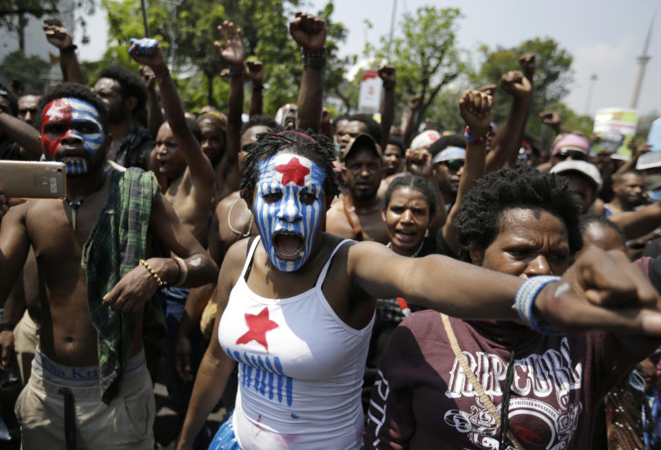 A Papuan activist with her face painted with the colors of the separatist Morning Star flag shouts slogans during a rally near the presidential palace in Jakarta, Indonesia, Thursday, Aug. 22, 2019. A group of West Papuan students in Indonesia's capital staged the protest against racism and called for independence for their region. (AP Photo/Dita Alangkara)