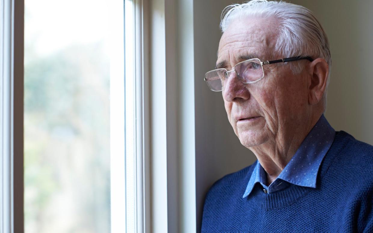 An elderly man looks out of the window - Highwaystarz-Photography/iStockphoto