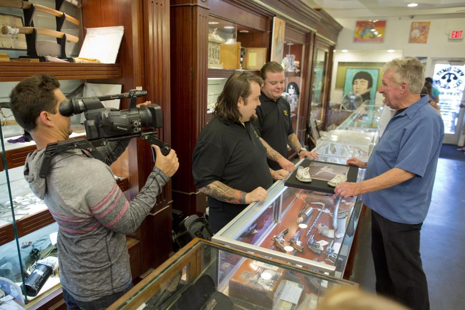 In this Wednesday, April 3, 2013, photo, cameraman Mark Matusiak shoots a scene between Chumlee, second from left, Corey Harrison, and customer Gene McCauliff of Las Vegas, for the reality tv series Pawn Stars, Wednesday, April 3, 2013, in Las Vegas. Pawn sales at the Gold & Silver Pawn Shop bring in about $20 million a year, up from the $4 million a year it made before the show aired.Turning small business owners into stars has become a winning formula for television producers, but the businesses featured in the shows are cashing in, too. Sales explode after just a few episodes have aired, transforming nearly unknown small businesses into household names. (AP Photo/Julie Jacobson)