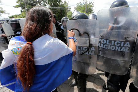 A demonstrator sprays on the shield of a riot police during a protest against Nicaraguan President Daniel Ortega's government in Managua, Nicaragua September 23, 2018. REUTERS/Oswaldo Rivas