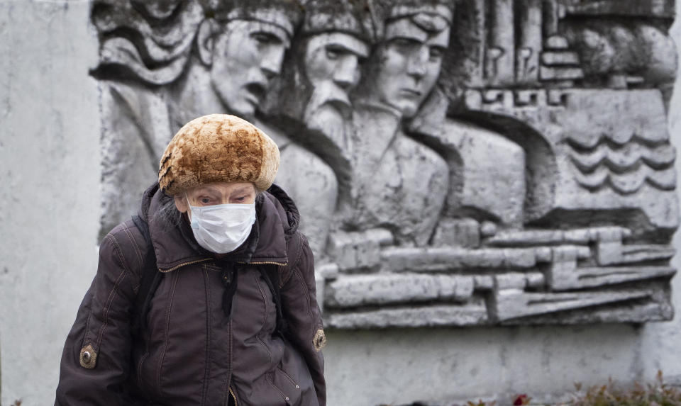 A woman wearing a face mask to protect against coronavirus walk past a Soviet era bas-relief in St. Petersburg, Russia, Thursday, May 21, 2020. (AP Photo/Dmitri Lovetsky)