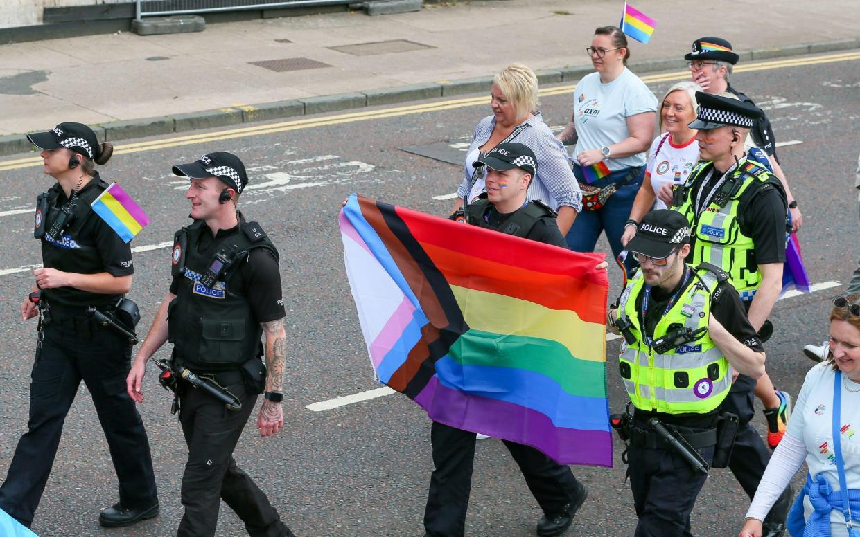 Police officers wave an LGBT flag on a Pride march in Glasgow - Findlay/Alamy Live News