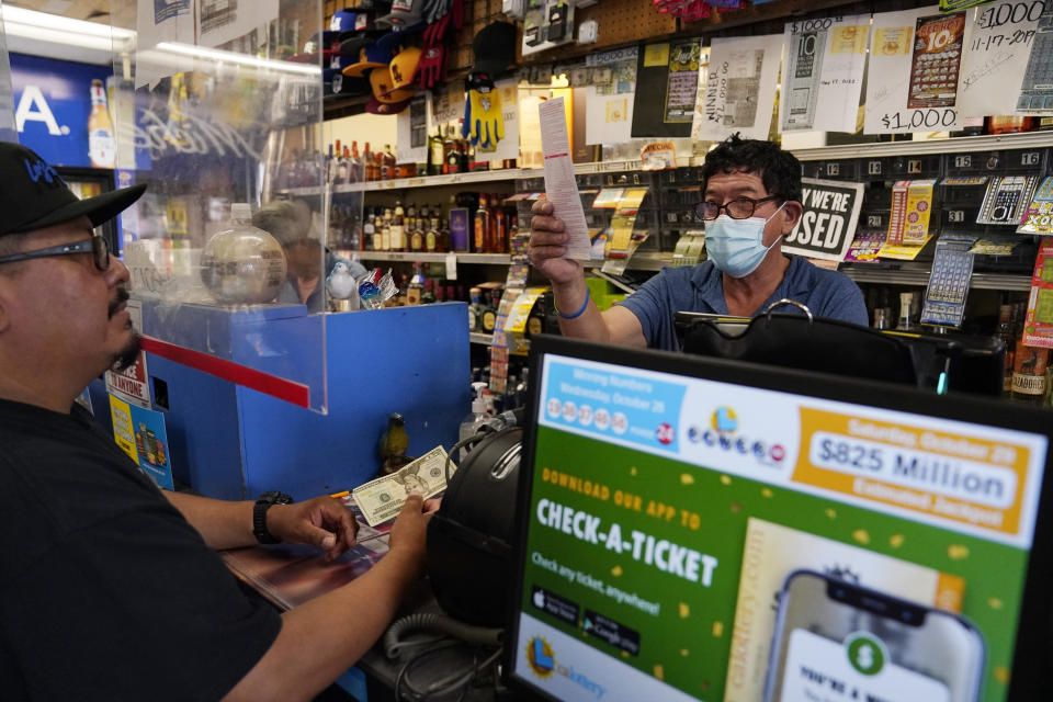 A customer buys lottery tickets at Bluebird Liquor, Friday, Oct. 28, 2022, in Hawthorne, Calif. Saturday's jackpot projected winnings of an estimated $825 million is the fifth-highest in U.S. history. (AP Photo/Mark J. Terrill)