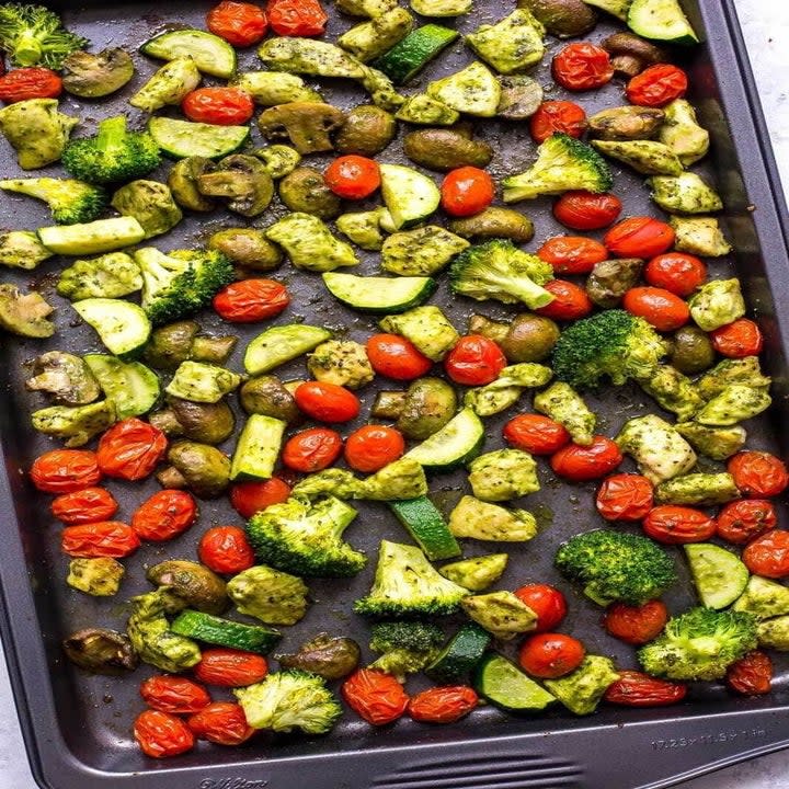 Pesto chicken, broccoli, and tomatoes on a sheet pan.