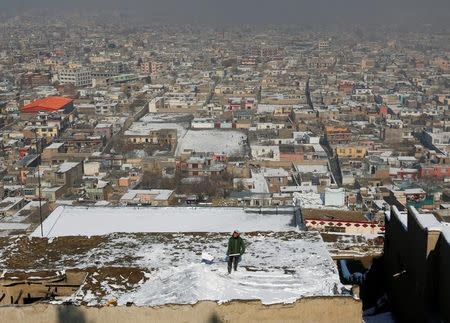 A boy removes snow on the roof of his house on a hilltop overlooking Kabul, Afghanistan January 16, 2017. REUTERS/Mohammad Ismail