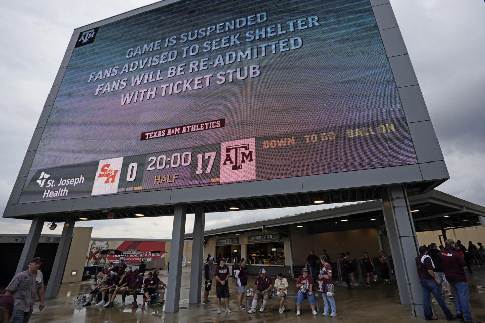 Fans sit under a scoreboard during a weather delay for an NCAA college football game between Sam Houston State and Texas A&M Saturday, Sept. 3, 2022, in College Station, Texas. (AP Photo/David J. Phillip)
