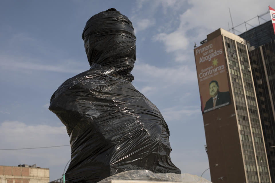 A bust of Fermin Diez Canseco, a military hero who fought in the War of the Pacific War, is seen wrapped in black plastic, on the Paseo de los Heroes boulevard in Lima, Peru, Saturday, Nov. 21, 2020. The municipality of Lima for the the first time in 485 years took precautions to protect historical monuments and statues, while Peru was mired in a whirlwind of demonstrations and a political crisis that resulted with three presidents in nine days. (AP Photo/Rodrigo Abd)