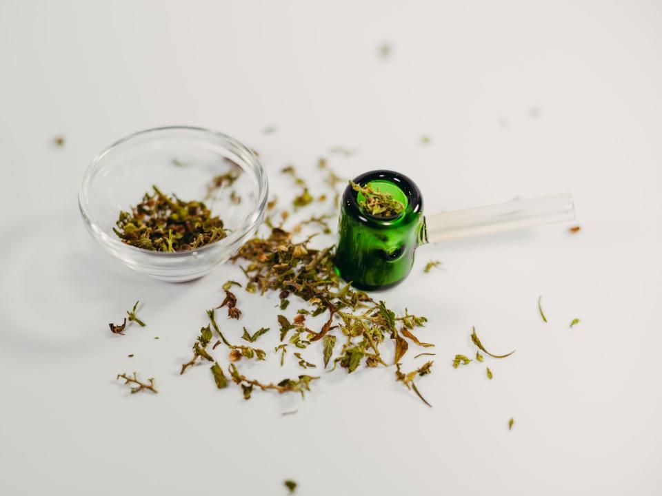 Glass cannabis pipe next to a clear bowl with ground weed in it.