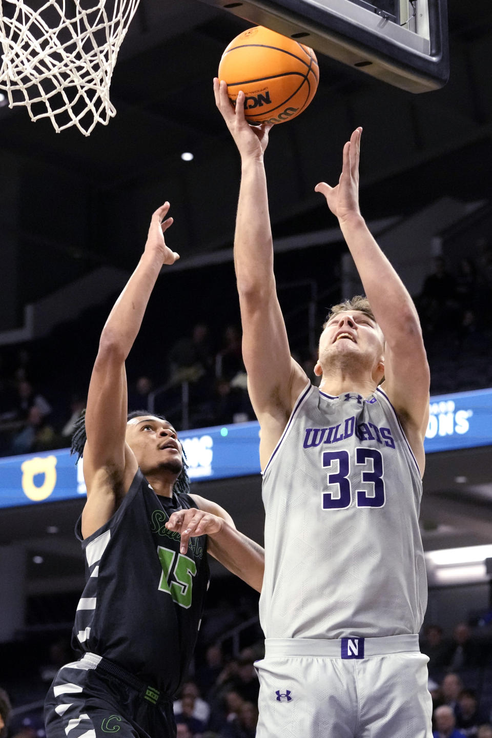 Northwestern forward Luke Hunger (33) shoots as Chicago State forward Noble Crawford guards during the first half of an NCAA college basketball game in Evanston, Ill., Wednesday, Dec. 13, 2023. (AP Photo/Nam Y. Huh)