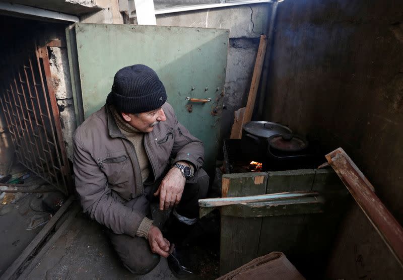 Local residents cook food at the entrance to the basement of an apartment building in Mariupol