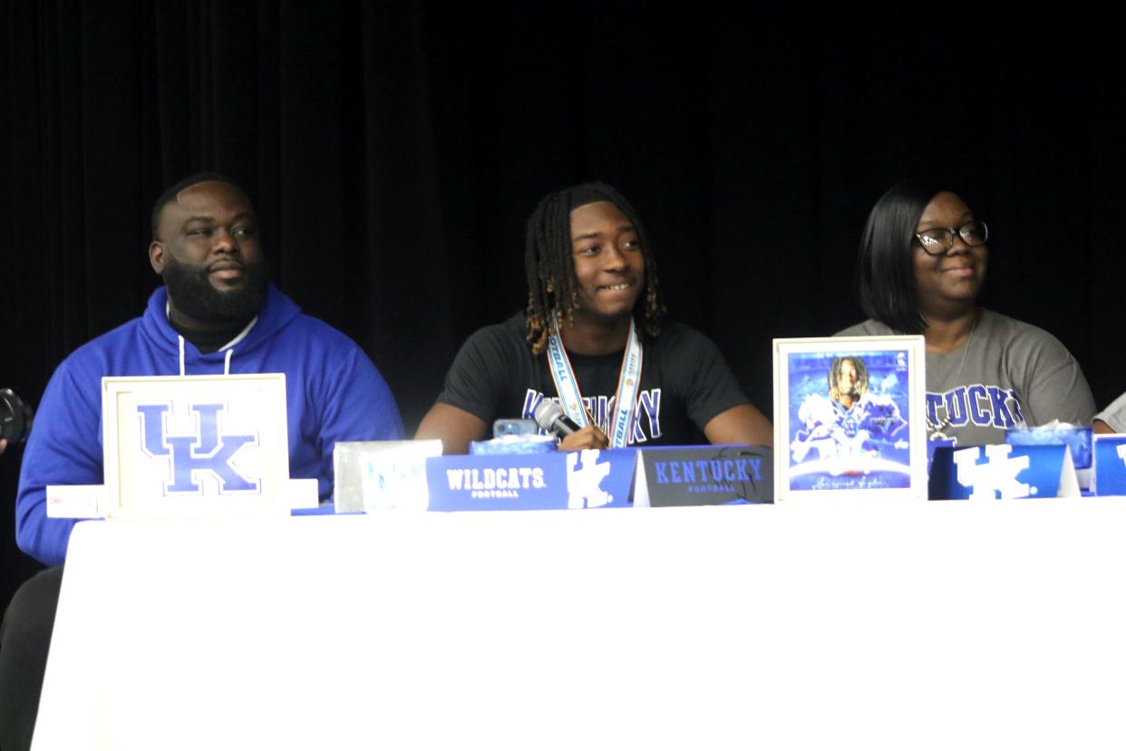 Flanked by his parents, Lake Wales defensive back Jaremiah Anglin Jr. listens as head coach Tavaris Johnson addresses the crowd on Thursday morning in the Lake Wales High School auditorium during a signing ceremony. Anglin signed with Kentucky.