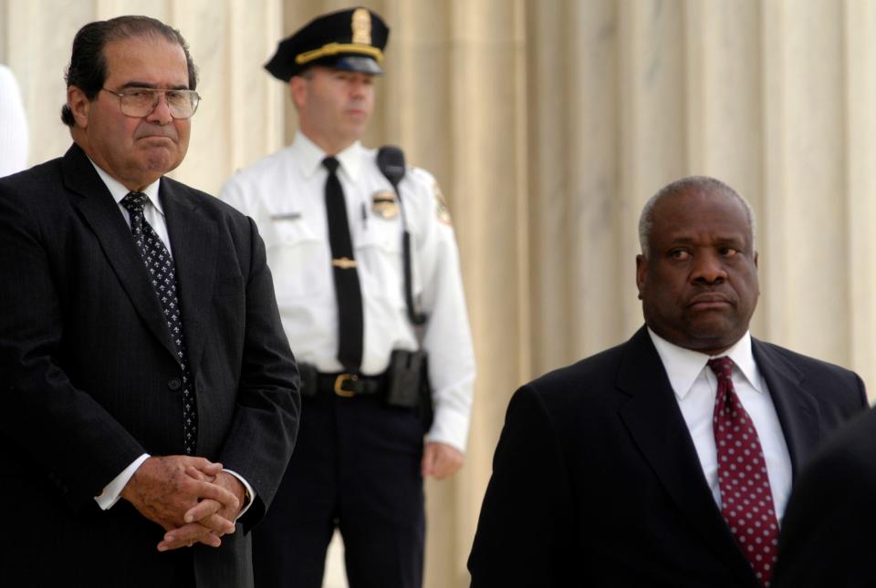 Associate Justices Antonin Scalia and Clarence Thomas stand on the steps of the Supreme Court as pallbearers carry the casket of Chief Justice of the United States William Rehnquist into the Supreme Court.