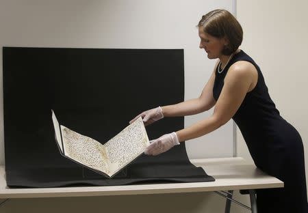 Conservator, Marie Sviergula holds a fragment of a Koran manuscript in the library at the University of Birmingham in Britain July 22, 2015. A British university said on Wednesday that fragments of a Koran manuscript found in its library were from one of the oldest surviving copies of the Islamic text in the world, possibly written by someone who might have known Prophet Mohammad. REUTERS/Peter Nicholls