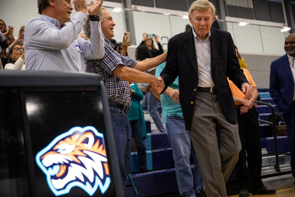 Mike Kunstadt, the 1973 Carroll high school basketball coach, shakes hands with Steven Loveless, a point guard, while being honored during a game at Carroll's new campus on Friday, Dec. 9, 2022, in Corpus Christi, Texas.