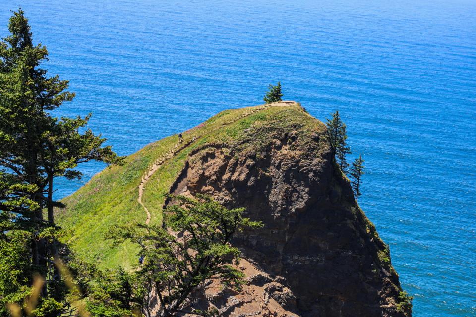 Dos senderistas llegan a la cima de God's Thumb al norte de Lincoln City, con vista a la costa de Oregon.