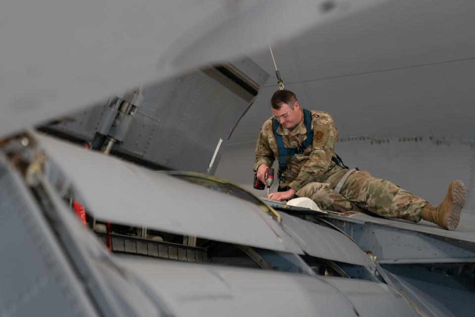 Attached to a harness, Master Sgt. Christian McGraw uses an impact driver to remove bolts from the wing of a KC-135 air refueling aircraft Thursday morning.