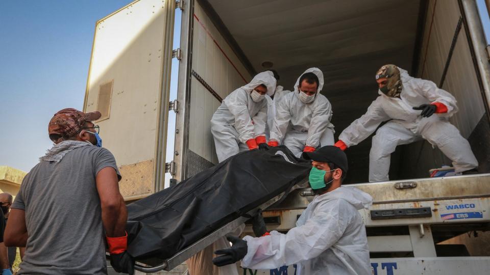 Arbeiter in Schutzkleidung beladen in Bagdad einen Kühlwagen mit Leichen von Menschen, die am Coronavirus gestorben sind.