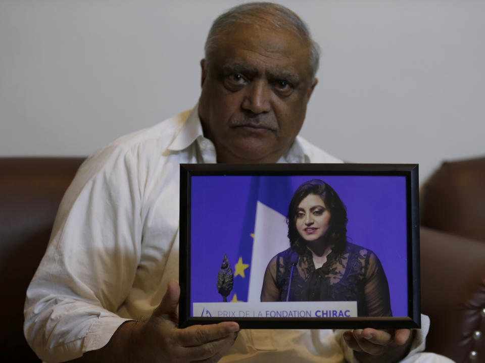 Professor Mohammad Ismail, father of a Pakistani human rights activist Gulalai Ismail, holds a picture of his daughter as he poses for a photo, in his home in Islamabad, Pakistan, Thursday, Oct. 17, 2019. A dozen plainclothes Pakistani security forces attempted to raid the former home of Gulalai Ismaila who recently fled to the United States seeking asylum. Gulalai's elderly parents say they were ordered to come outside "just to talk," but refused. Raids like the one early Thursday in the capital of Islamabad are part of an expanding push by Pakistan's security services to crack down on anyone who voices criticism of their activities. (AP Photo/Anjum Naveed)