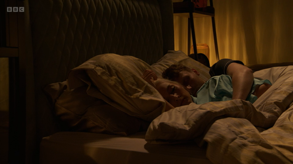 Jay Brown and Nadine cuddling in bed.